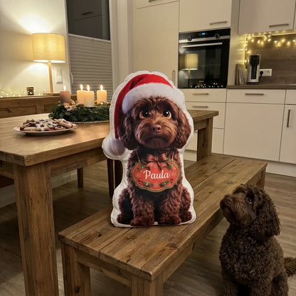 Weihnachtskissen Hund mit roter Mütze auf der Küchenbank, der lockige Hund sitzt davor