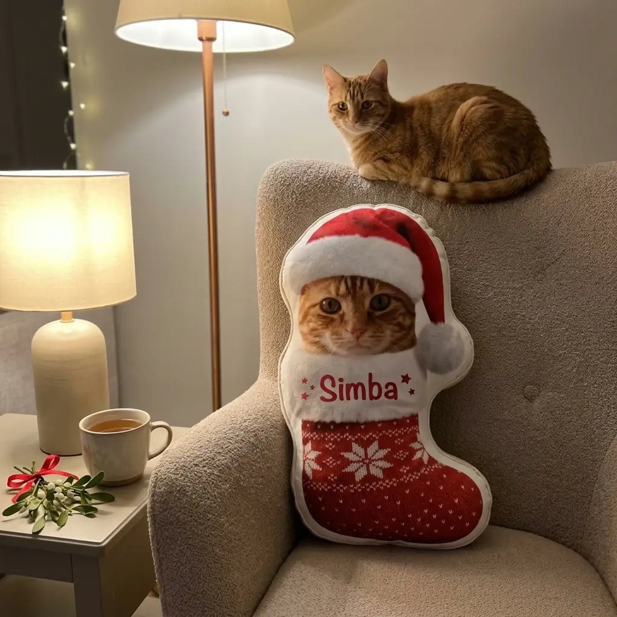 Kissen mit Katzenfoto im roten Weihnachtsstiefel im Sessel, rote Katze liegt auf der Lehne