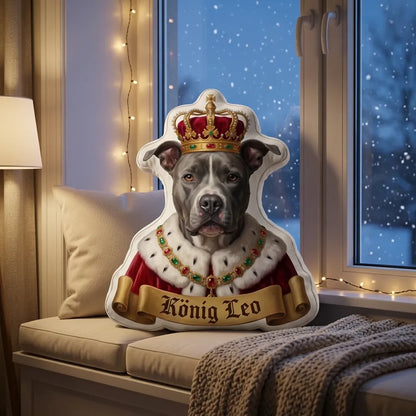 Kissen in Hundeform als König mit goldener Krone auf der Fensterbank im Schnee