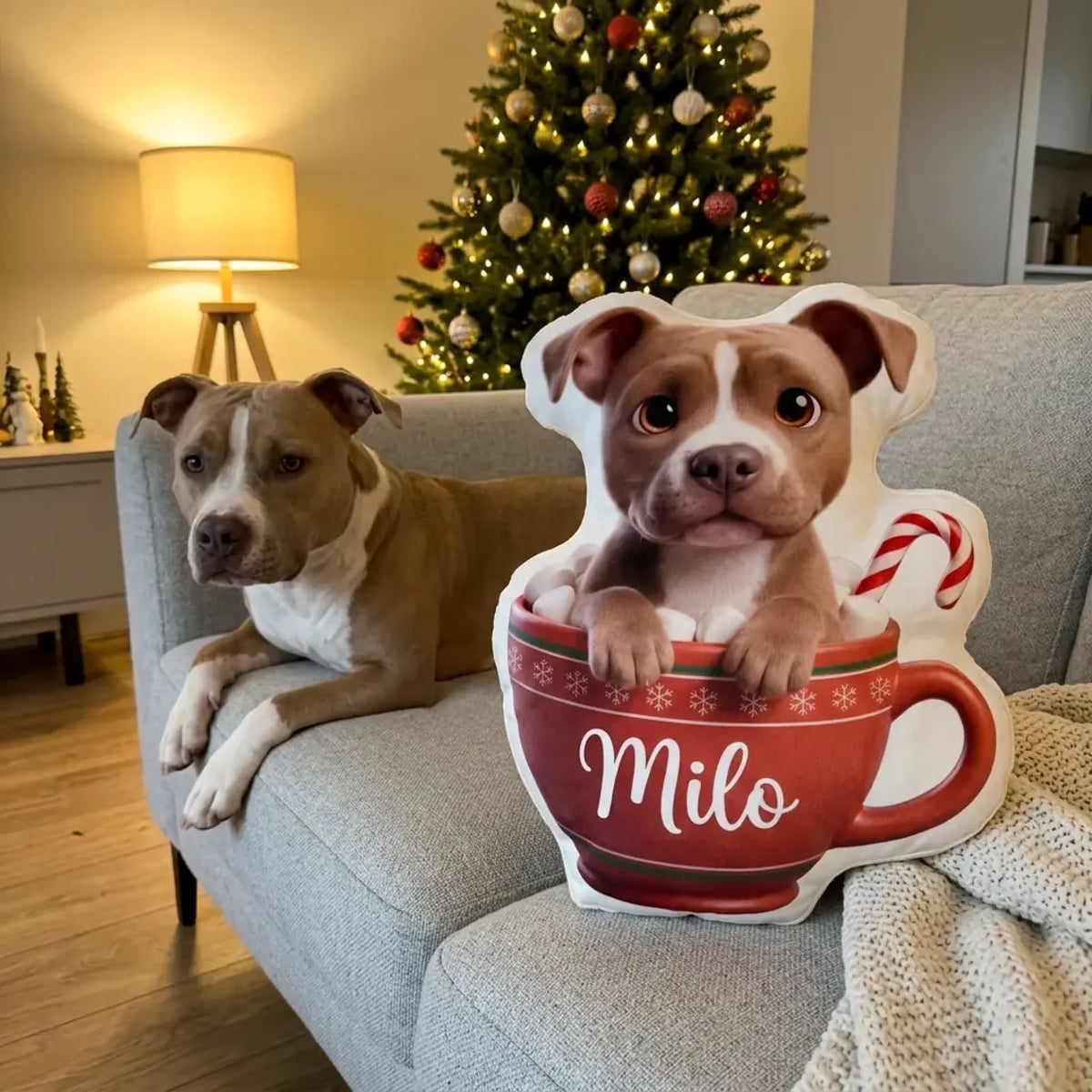Formkissen Kakao-Becher mit Hund im roten Becher und Name auf dem Sofa, der Hund liegt daneben
